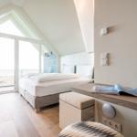 Schlafzimmer mit Doppelbett, Terrassentür und Schreibtisch.