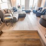 Eingangsbereich mit Holztreppe, Sofa, Kamin und Terrasse.