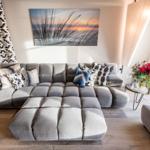 Großer grauer Sofa-Bereich mit Kissen und Wandbild