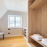 Schlafzimmer mit Holzboden, Kleiderschrank und Sitzgelegenheit.