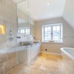 Dusche mit Steinwand, Waschbecken und freistehende Badewanne.