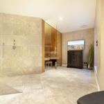 Dusche mit Regenduschkopf, Sauna und Fernseher im Raum.