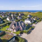 Haus mit Dach und Garten, umgeben von Grünflächen und Meer
