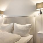 Schlafzimmer mit Bett, Kopfteil und Wandlampen.