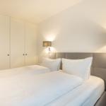 Schlafzimmer mit Bett, Kleiderschrank und Wandlampen.
