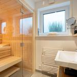 Dusche mit Sauna, Waschbecken und Fenster mit Pflanze.