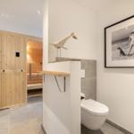 Bad mit Dusche, Toilette und Sauna im Hintergrund.
