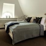Bedroom with sloped ceiling, window, bed, and nightstand.