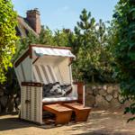 Hanging chair with awning and cushions on paved courtyard.