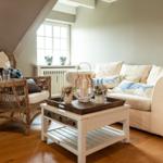 Living room with armchair, sofa, and table under sloped ceiling.