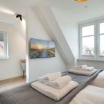 Schlafzimmer mit Dachschrägen, Fenstern und Bett mit Handtüchern.