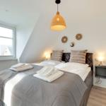 Schlafzimmer mit Dachschräge, Bett, Fenster und Lampe.