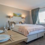 Schlafzimmer mit Bett, Tisch und Fenster
