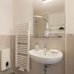 Badezimmer mit Dusche, Waschbecken und Heizkörper