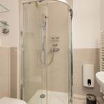 Badezimmer mit Dusche, Waschbecken und Heizkörper
