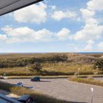 Blick von Balkon auf Parkplatz und Dünen mit Meer im Hintergrund.