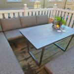 Terrasse mit Sitzgruppe und Tisch. Holzgeländer und Befestigung an Backsteinmauer.