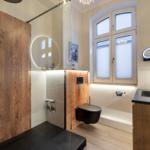 Badezimmer mit Dusche, Toilette und Waschbecken. Holzwände und großes Fenster.
