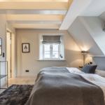 Schlafzimmer mit Dachschrägen, Bett, Fernseher und Fenster.