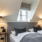 Schlafzimmer mit Dachschräge, Bett, zwei Nachttische und Fenster.