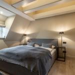 Schlafzimmer mit Dachschrägen, Bett, Nachttischen und Fenster.