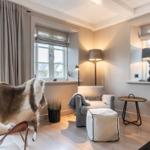 Wohnzimmer mit Sessel, Stuhl mit Fell, Tisch und Lampen.
