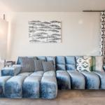 Ein Wohnzimmer mit einem blauen Sofa, Kissen und einem Wandbild mit Fischen.