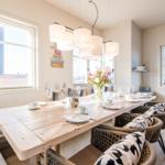 Essbereich mit Holztisch, Stühlen und Fenstern. Tisch gedeckt mit Tassen und Gläsern.