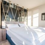 Schlafzimmer mit Doppelbett, Holzboden und Wandspiegel