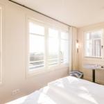 Schlafzimmer mit Blick aufs Meer und Fenster mit Vorhängen.
