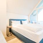 Schlafzimmer mit Doppelbett, Balkon und moderner Einrichtung.