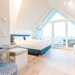 Schlafzimmer mit Balkon, Bett, Schreibtisch und Holzboden.