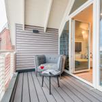 Terrasse mit Sitzgelegenheit und Blick ins Innere. Holzdecke und Glaswände.