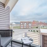 Terrasse mit Stuhl und Tisch, Blick auf Wohnhäuser und Straße.