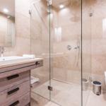Bad mit Dusche, Waschbecken und Toilette. Steinwand und Holzschrank.