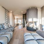 Wohnzimmer mit Sofa, Sessel und Kamin. Holzboden und moderne Einrichtung.