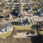 Aerial view of houses with roofs and green areas in a residential area.