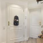 Entrance area with white doors and shoe holder on the door.