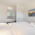 Room with double bed, mirror, and wall picture. White walls and ceiling.
