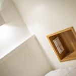 Wall with wooden frame and socket next to bed and wall lamp