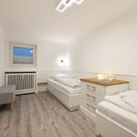 Room with two beds, wardrobe and window. Wall picture and wooden floor.