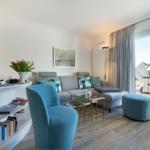 Living room with sofa, blue seating, and view of terrace.