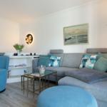 Living room with gray sofa, blue seating, and glass table.
