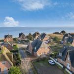 Dorf mit strohgedeckten Häusern am Meer unter blauem Himmel