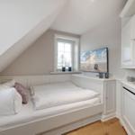 Schlafzimmer mit Dachschräge, Bett, Fenster und Fernseher.