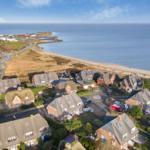 Häuser am Strand mit Blick aufs Meer und eine Straße.