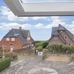 Roter Backsteinhaus mit grauem Dach, umgeben von Grünflächen und Steinmauern.