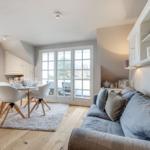 Wohn- und Essbereich mit Sofa, Tisch und Stühlen, Blick auf Balkon.