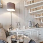 Ein Wohnbereich mit grauem Sofa, weißem Sideboard und einer Treppe.