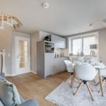 Küche mit Essbereich, weiße Stühle, Spindelstiege und Holzboden.